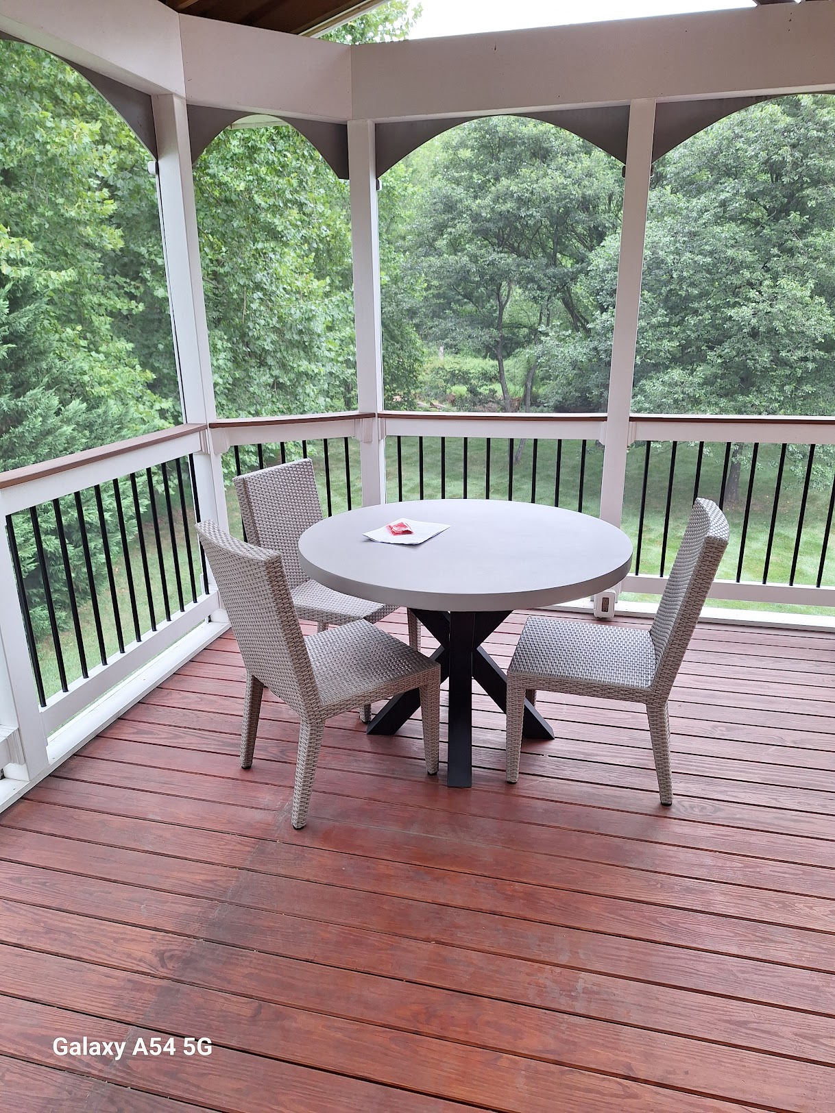 Screened-in porch with custom round dining table overlooking a wooded backyard